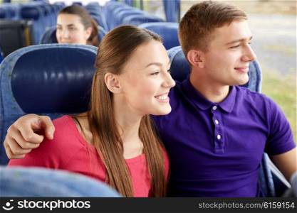transport, tourism, road trip and people concept - happy teenage couple or tourists hugging in travel bus and looking through window
