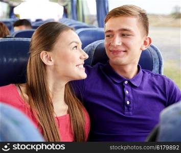 transport, tourism, road trip and people concept - happy teenage couple or tourists in travel bus hugging and talking