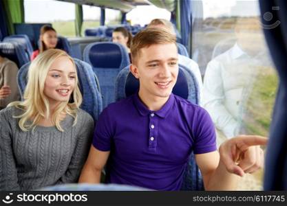 transport, tourism, road trip and people concept - happy teenage couple with group of passengers or tourists in travel bus