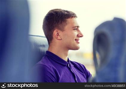 transport, tourism, road trip and people concept - happy young man sitting in travel bus or train and looking through window. happy young man sitting in travel bus