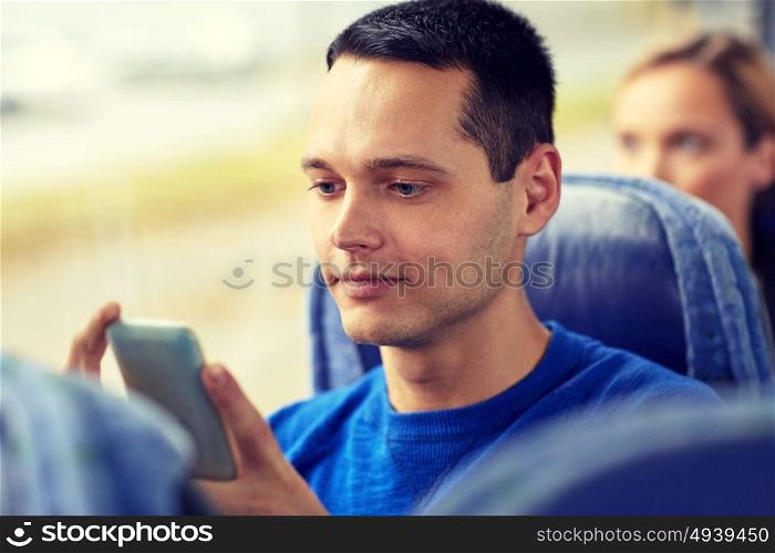 transport, tourism, road trip and people concept - happy young man sitting in travel bus or train with smartphone. happy man sitting in travel bus with smartphone