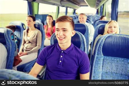 transport, tourism, road trip and people concept - happy young man sitting in travel bus or train. happy young man sitting in travel bus or train