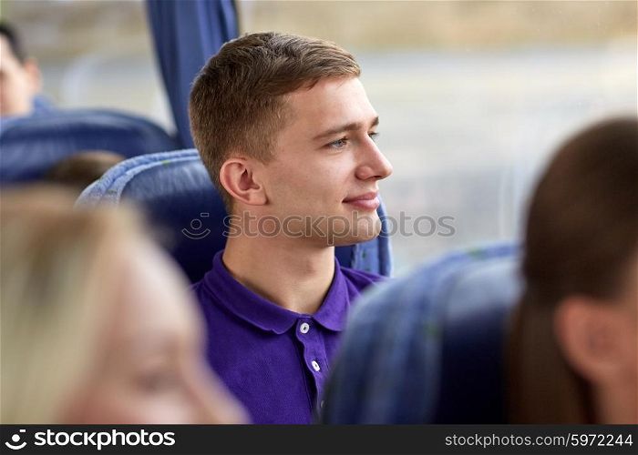transport, tourism, road trip and people concept - happy young man sitting in travel bus and looking through window