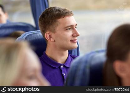 transport, tourism, road trip and people concept - happy young man sitting in travel bus and looking through window
