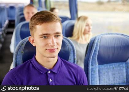 transport, tourism, road trip and people concept - happy young man sitting in travel bus or train