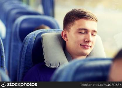 transport, tourism, road trip and people concept - happy young man sleeping in travel bus with pillow. happy young man sleeping in travel bus with pillow