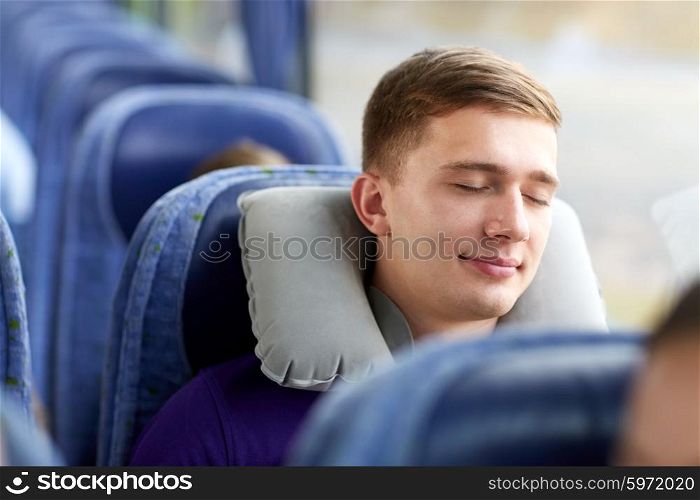 transport, tourism, road trip and people concept - happy young man sleeping in travel bus with pillow