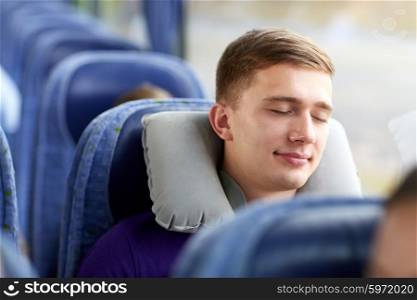 transport, tourism, road trip and people concept - happy young man sleeping in travel bus with pillow