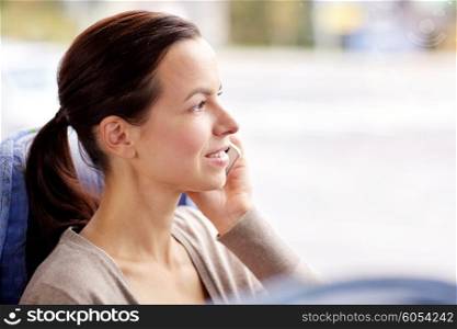 transport, tourism, road trip and people concept - happy young woman in travel bus or train calling on smartphone