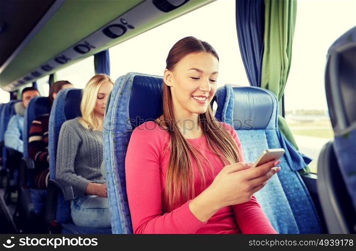transport, tourism, road trip and people concept - happy young woman sitting in travel bus with smartphone. happy woman sitting in travel bus with smartphone