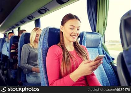 transport, tourism, road trip and people concept - happy young woman sitting in travel bus with smartphone. happy woman sitting in travel bus with smartphone