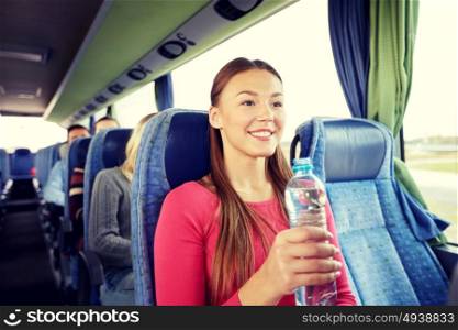 transport, tourism, road trip and people concept - happy young woman with water bottle in travel bus. happy young woman with water bottle in travel bus