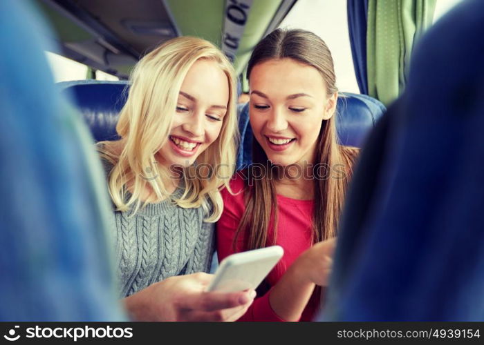 transport, tourism, road trip and people concept - happy young women or friends in travel bus texting or reading message on smartphone. happy young women in travel bus with smartphone