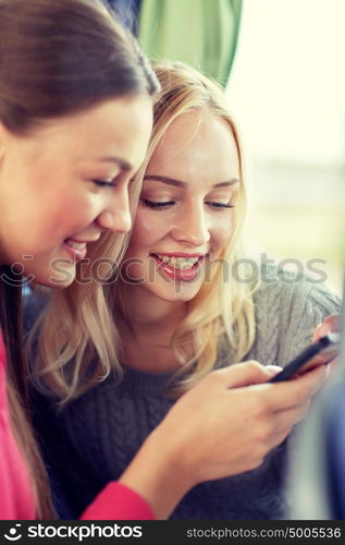 transport, tourism, road trip and people concept - happy young women or friends in travel bus texting or reading message on smartphone. happy young women in travel bus with smartphone