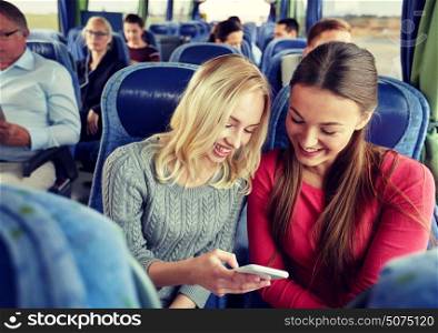 transport, tourism, road trip and people concept - happy young women or friends in travel bus texting or reading message on smartphone. happy young women in travel bus with smartphone