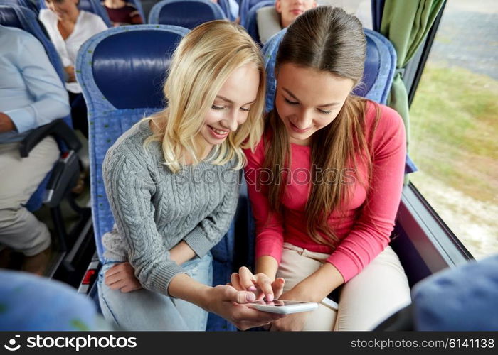 transport, tourism, road trip and people concept - happy young women or friends in travel bus texting or reading message on smartphone