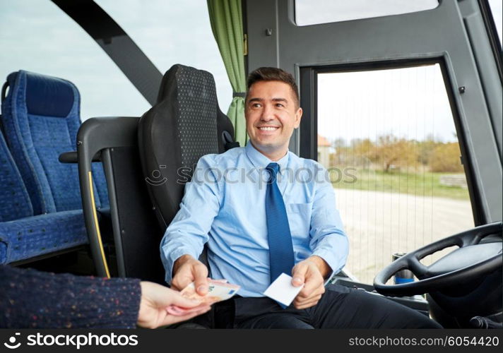 transport, tourism, road trip and people concept - smiling bus driver selling ticket and taking money from passenger