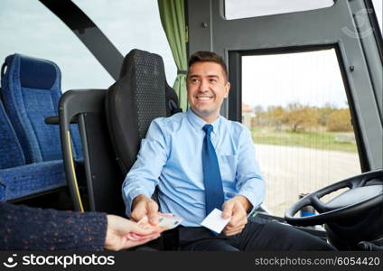 transport, tourism, road trip and people concept - smiling bus driver selling ticket and taking money from passenger