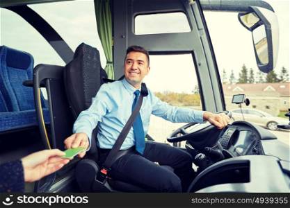 transport, tourism, road trip and people concept - smiling bus driver taking ticket or plastic card from passenger. bus driver taking ticket or card from passenger