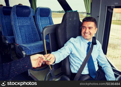 transport, tourism, road trip and people concept - smiling bus driver taking ticket or plastic card from passenger. bus driver taking ticket or card from passenger