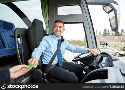 transport, tourism, road trip and people concept - smiling bus driver taking ticket or plastic card from passenger