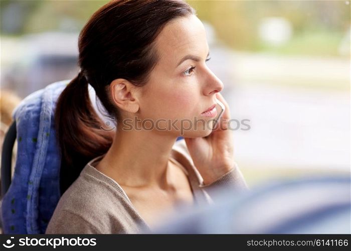 transport, tourism, road trip and people concept - young woman in travel bus or train calling on smartphone