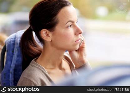 transport, tourism, road trip and people concept - young woman in travel bus or train calling on smartphone