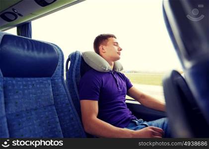 transport, tourism, road trip, rest and people concept - happy young man sleeping in travel bus with inflatable pillow. happy young man sleeping in travel bus with pillow