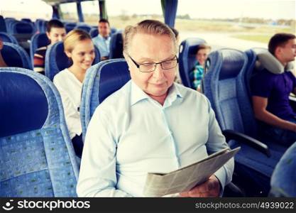 transport, tourism, trip and people concept - senior man reading newspaper in travel bus. happy senior man reading newspaper in travel bus