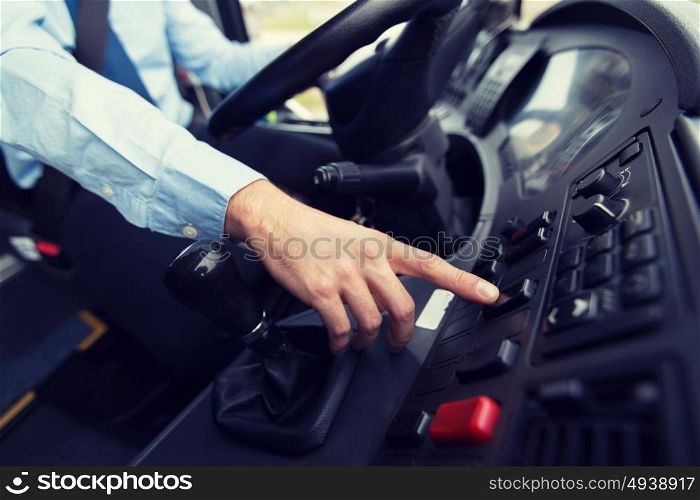 transport, transportation, tourism, road trip and people concept - close up of bus driver driving passenger bus and pushing button on dashboard. close up of driver driving passenger bus