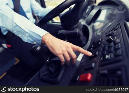 transport, transportation, tourism, road trip and people concept - close up of bus driver driving passenger bus and pushing button on dashboard. close up of driver driving passenger bus