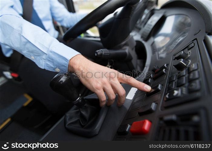 transport, transportation, tourism, road trip and people concept - close up of bus driver driving passenger bus and pushing button on dashboard