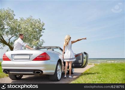 transport, travel, road trip and people concept - happy man and woman near cabriolet car at sea side