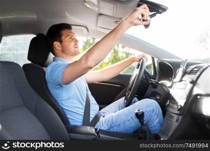transport, vehicle and driving concept - man or car driver adjusting mirror in summer. man or car driver adjusting mirror