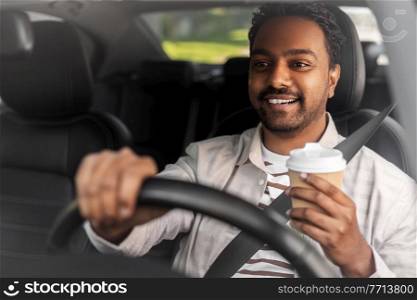 transport, vehicle and people concept - happy smiling indian man or driver with takeaway coffee cup driving car. happy indian man or driver with coffee driving car