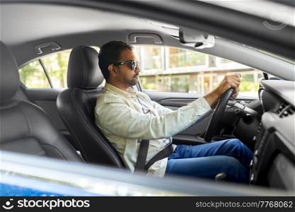 transport, vehicle and people concept - indian man or driver in sunglasses driving car. indian man or driver in sunglasses driving car