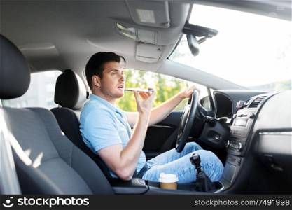 transport, vehicle and people concept - smiling man or driver driving car and recording message using voice command recorder on smartphone. man driving car and recording voice by smartphone