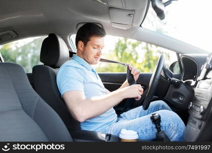 transport, vehicle and safe driving concept - man or car driver fastening safety seat belt in summer. man or car driver fastening seat belt