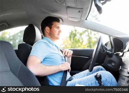 transport, vehicle and safe driving concept - man or car driver fastening safety seat belt in summer. man or car driver fastening seat belt