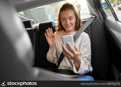 transport, vehicle and technology concept - happy smiling woman or female passenger in taxi car having video call on smartphone. happy woman in car having video call on smartphone