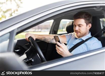 transport, vehicle and technology concept - smiling man or driver driving car and using smartphone. man driving car and using smartphone