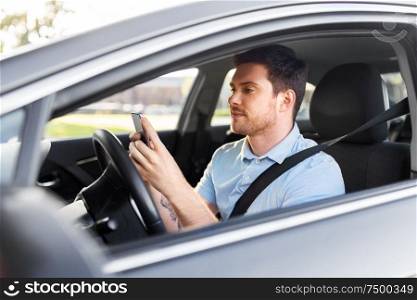 transport, vehicle and technology concept - smiling man or driver driving car and using smartphone. man driving car and using smartphone