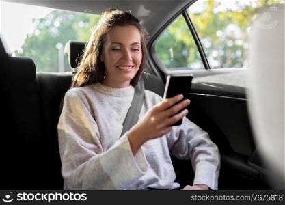 transport, vehicle and technology concept - smiling woman in taxi car using smartphone. smiling woman using smartphone in taxi car