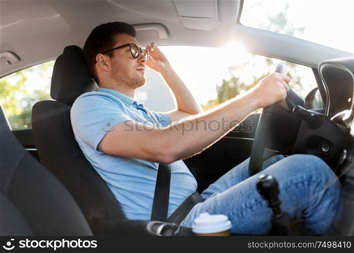 transport, vehicle and vision concept - man or driver in glasses driving car in summer. man or driver in glasses driving car in summer