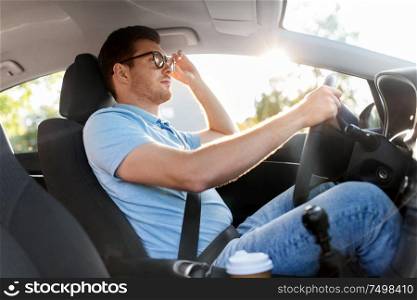 transport, vehicle and vision concept - man or driver in glasses driving car in summer. man or driver in glasses driving car in summer
