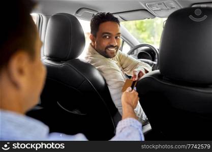 transportation and cash-free payment concept - indian male taxi car driver taking credit card from passenger. taxi car driver taking credit card from passenger