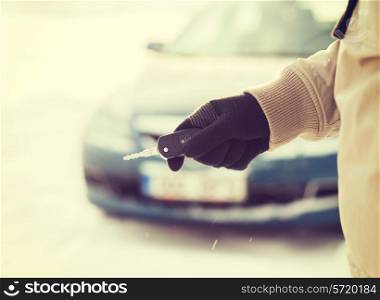 transportation and ownership concept - closeup of man hand with car key outdoors