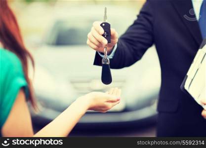 transportation and ownership concept - customer and salesman with car key outside