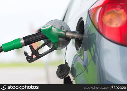 transportation and ownership concept - pumping gasoline fuel in car at gas station