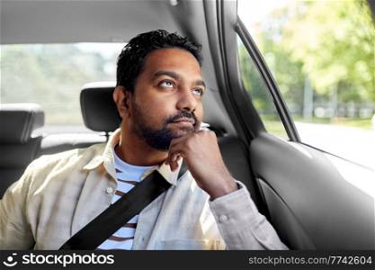 transportation and people concept - dreaming indian male passenger in taxi car. dreaming indian male passenger in taxi car